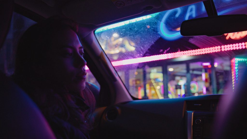 front shot interior car scene at night near carnival lights